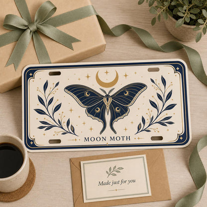 Moon Moth custom license plate in an elegant gift scene with kraft wrapping, sage ribbon, and message card.