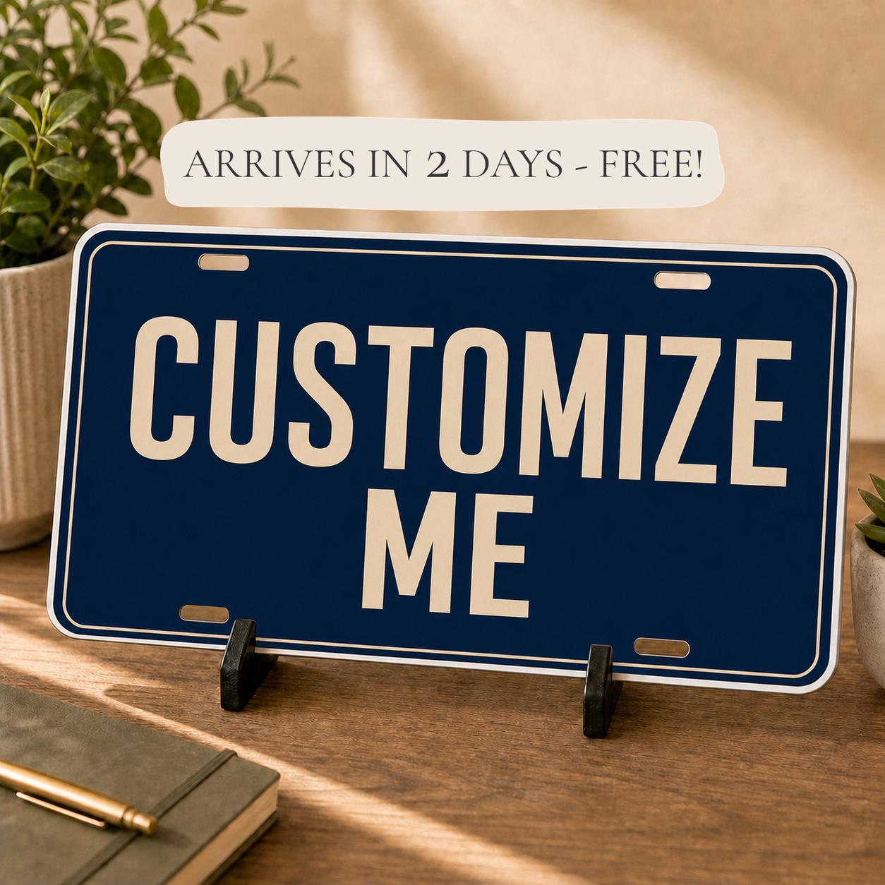Custom aluminum novelty license plate with a navy Customize Me design and a two-day arrival banner above the plate.