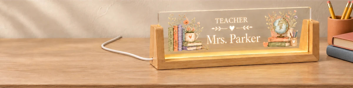 Illuminated Mrs. Parker teacher acrylic nameplate in a natural wood base beside a terracotta pencil cup and schoolbooks